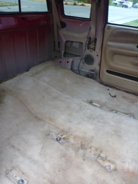1997 Dodge 2500 - The interior of a 1997 Dodge 2500 pickup truck is shown from the rear, revealing its worn carpet and red interior panels.