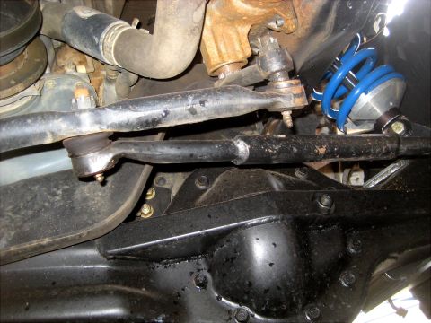 1996 Ford Bronco - Undercarriage view of steering linkage and suspension components, including a bright blue coilover shock.