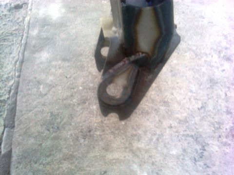 1986 Ford Bronco - A close-up view of a dark metal suspension component, possibly a radius arm bracket, with visible welding marks.