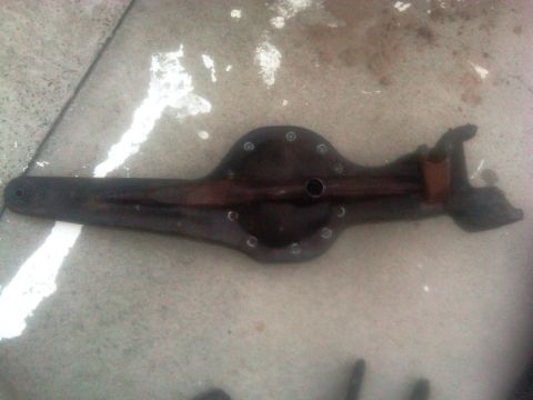 1986 Ford Bronco - A dark rear axle differential housing lies on a concrete surface with white paint splatters.
