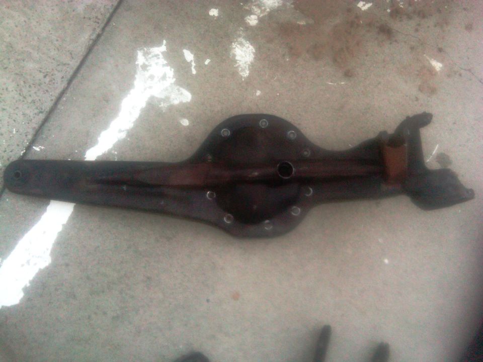 Dark rear axle differential housing on concrete. Water stains and white paint splatters are visible