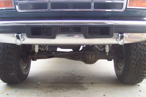 1995 Ford Bronco - Close-up view of the front axle and bumper of a truck, showing tow hooks and off-road tires.