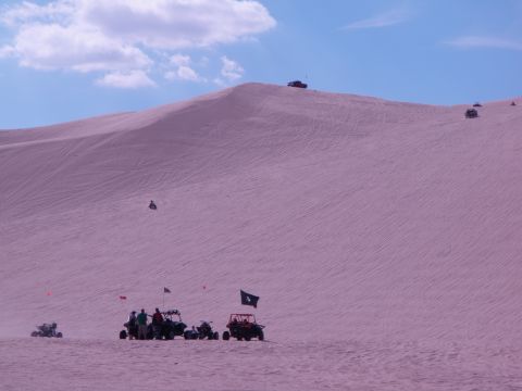 1982 Ford Bronco - Off-road vehicles navigate a vast sand dune landscape under a partly cloudy sky.