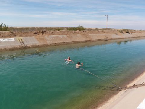 1982 Ford Bronco - People swimming in a canal, with desert scenery in the background.