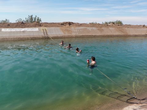 1982 Ford Bronco - A group of people enjoy a swim in a clear blue canal under a bright sky.