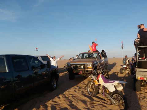 1982 Ford Bronco - A group of people enjoy a day at the sand dunes, gathered around a vintage SUV and other vehicles.