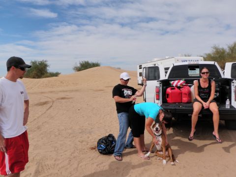 1982 Ford Bronco - People and a dog gather near a pickup truck and RV in a desert landscape.
