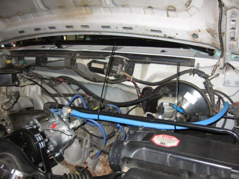 1995 Ford Bronco - Engine bay detail with AC compressor and brake booster assembly. Visible wiring and blue-hoses.
