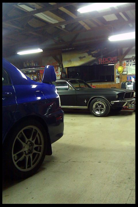 2006 Mitsubishi Evolution - A blue Mitsubishi Evo and a black 1967 Ford Mustang are parked inside a garage.
