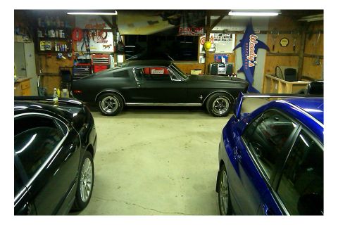 2006 Mitsubishi Evolution - A black 1967 Ford Mustang is parked in a garage alongside two other vehicles.