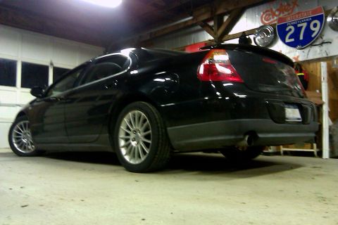 2006 Mitsubishi Evolution - A black sedan is viewed from the rear in a garage, with a "Supermotors.net" watermark visible.