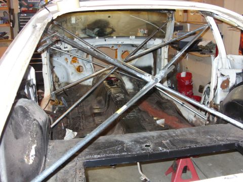 1978 Ford Mustang II - The interior of a car is visible, stripped down and fitted with a roll cage, resting on red jack stands.