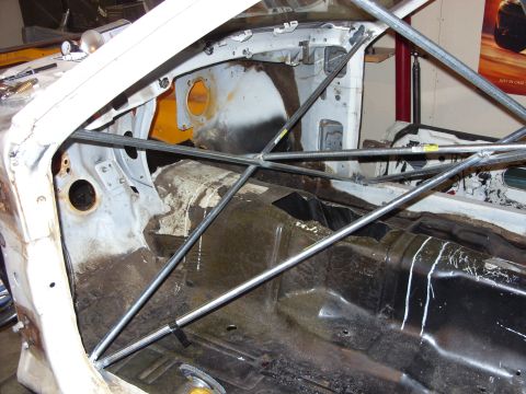 1978 Ford Mustang II - The interior of a car is shown, a prominent roll cage structure and the bare floor pan.