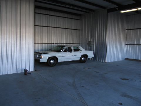 1991 Ford LTD Crown Victoria - A white 1991 Ford Crown Victoria LTD is parked inside a corrugated metal building.