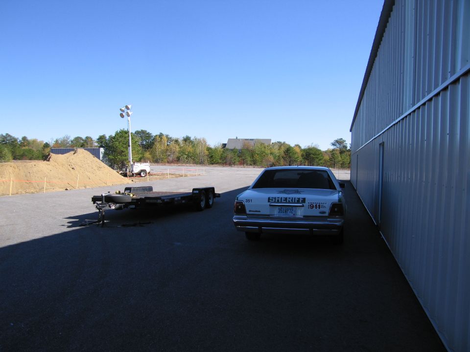 1991 Ford Crown Victoria LTD police car, rear view, parked next to a metal building