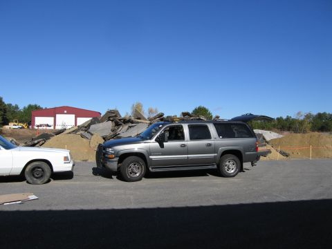 1991 Ford LTD Crown Victoria - A gray SUV is parked beside a white car with a construction debris pile behind them.