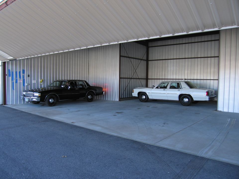 Black and white sedans parked inside a metal structure