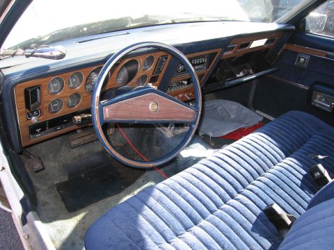 1991 Ford LTD Crown Victoria - Interior view of a car with a blue velour bench seat and a wood-grain dashboard.