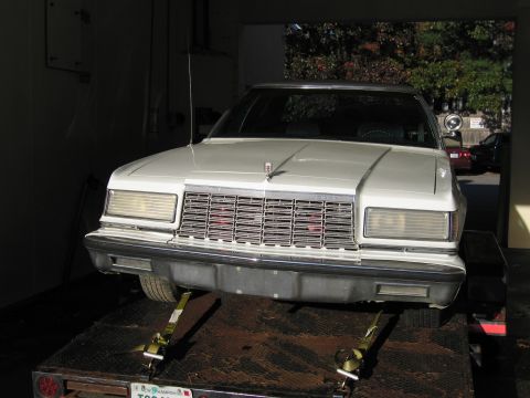 1991 Ford LTD Crown Victoria - This white sedan, likely from the early 1980s, is positioned on a trailer for transport.