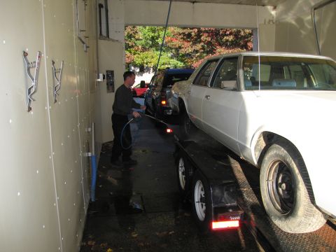 1991 Ford LTD Crown Victoria - A white 1991 Ford Crown Victoria LTD is being washed while on a trailer, with another vehicle visible behind it.