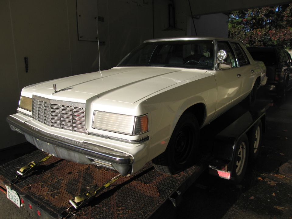 White sedan on a trailer, front grille visible