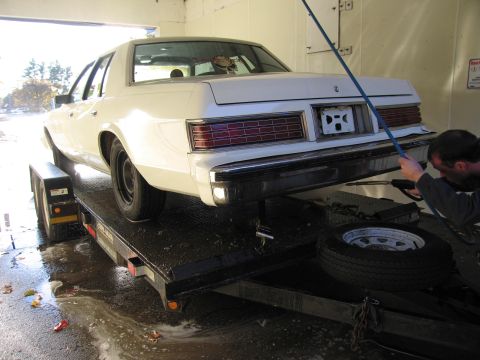1991 Ford LTD Crown Victoria - A white sedan is being washed while on a trailer.