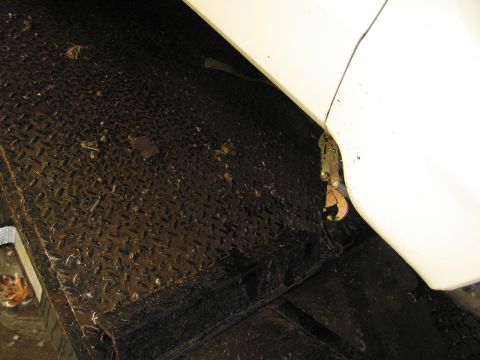 1991 Ford LTD Crown Victoria - A metal tie-down strap secures a vehicle to a trailer deck, showing a close-up of the attachment point.