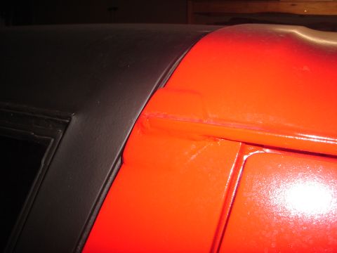 1989 Ford Bronco - Close-up of a seam between black and orange vehicle body panels, indicating repair work.