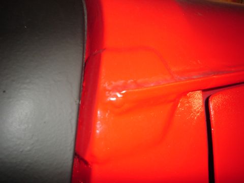 1989 Ford Bronco - Detail of a red vehicle's body panel, highlighting a crack and repair work.