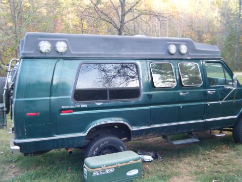1981 Ford E350 - This van has a custom camper shell with multiple lights and windows, parked outdoors.