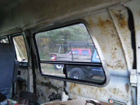 1981 Ford E350 - View from inside a van shows two trucks parked outdoors, one red and one blue.