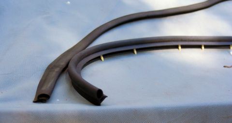 1976 Ford Ranchero - Two lengths of black hollow-bulb rubber weatherstrip laid on a light gray sheet, with the ends cut square to show the seal profile. The low…