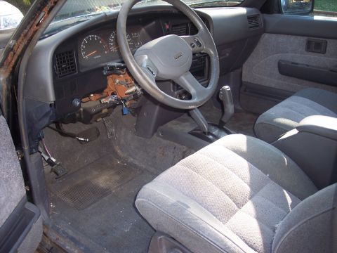2006 Chevrolet Corvette - The interior of an older vehicle shows a damaged dashboard and worn seats.