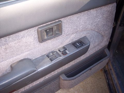 2006 Chevrolet Corvette - Close-up of a car's interior door panel, showing fabric texture and control buttons.