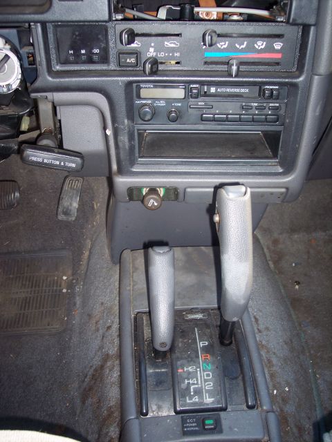 2006 Chevrolet Corvette - The interior of a vehicle shows the center console, including the automatic transmission shifter, radio, and climate control panel.