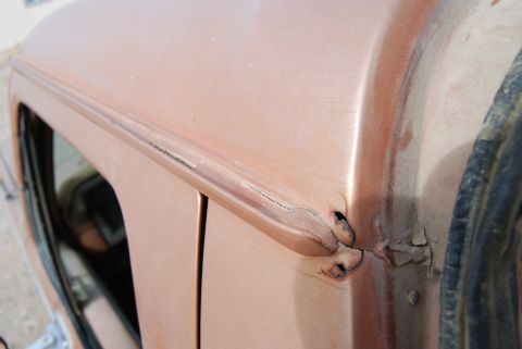 1982 Ford Bronco - Close-up of a vehicle's side panel showing significant rust and damage.