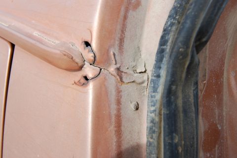1982 Ford Bronco - Close-up of a damaged door jamb, showing cracked paint and signs of rust.