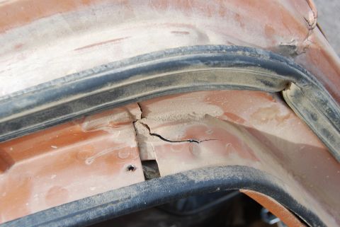 1982 Ford Bronco - A close-up view shows damage to the vehicle's bodywork, with a visible crack in the orange paint.