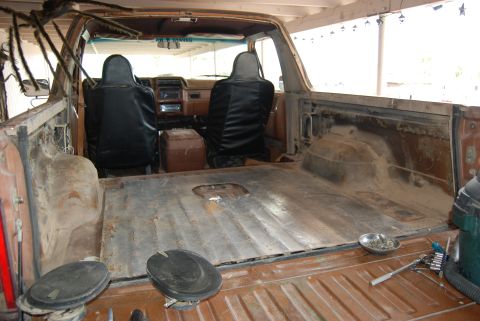 1982 Ford Bronco - The interior of a truck shows the empty bed area and the front seats, with a large spider decoration hanging from the ceiling.
