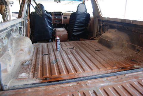 1982 Ford Bronco - The interior of a weathered SUV reveals a cargo bed and dashboard, with a can of spray paint on the floor.
