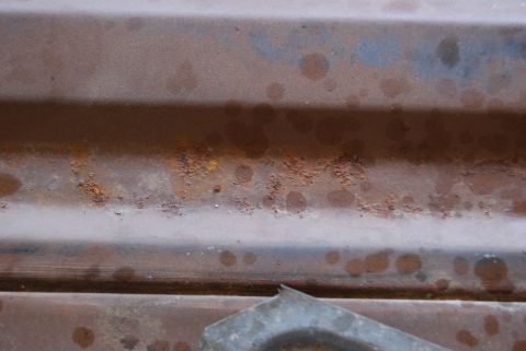 1982 Ford Bronco - Close-up of a heavily rusted metal panel, showing signs of wear and discoloration.
