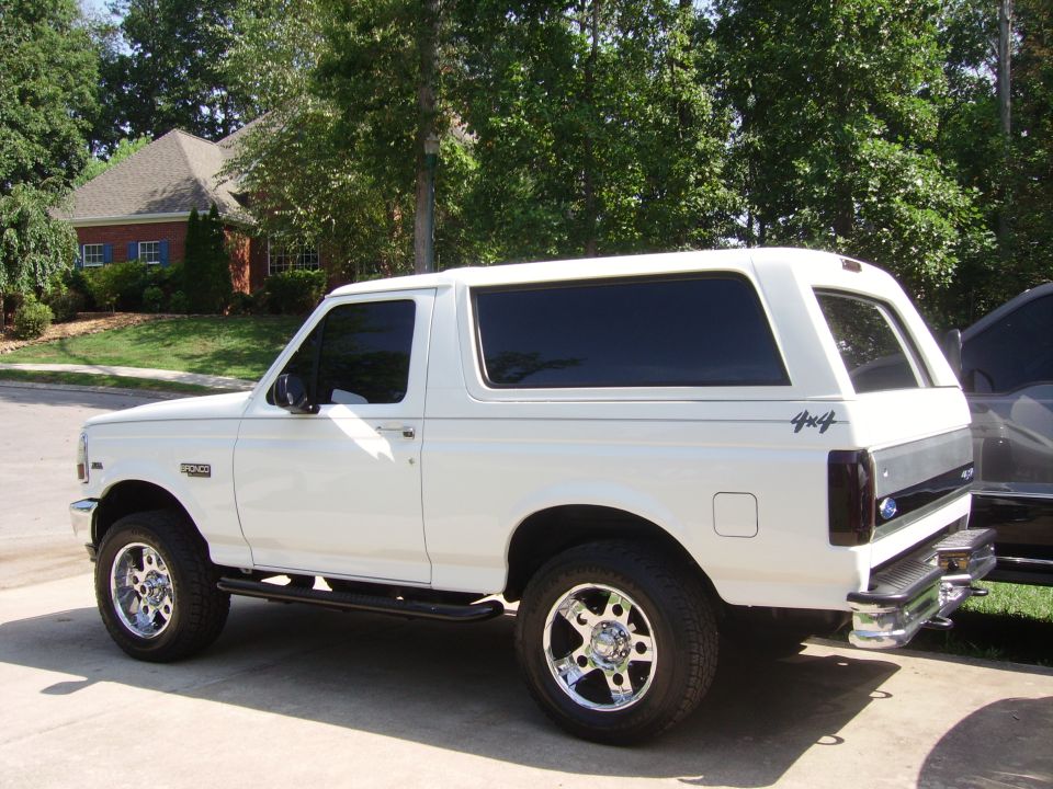 White Ford Bronco, side view, aftermarket wheels, tinted windows, 4x4 decal