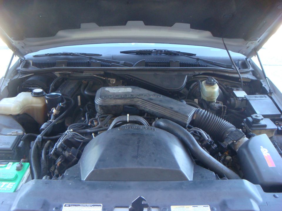Engine bay of a vehicle showing intake, master cylinder and battery