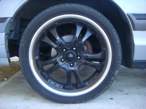 1994 Mercury Grand Marquis - Close-up of a black aftermarket wheel with a silver lip on a car. The registry claims it is a 1994 Mercury Grand Marquis, but this is not v…