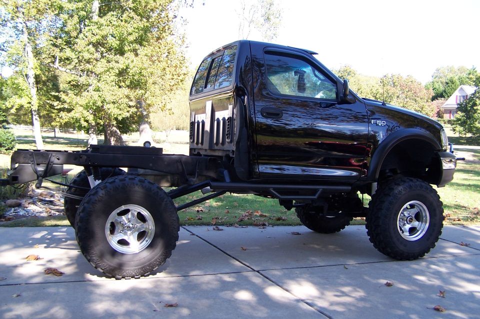 Black Ford F-150 with no bed, lifted on large tires