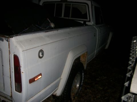 1976 Jeep J-10 - Rear view of a white 1976 Jeep J-10 pickup truck, showing its distinctive body lines and fuel filler door.