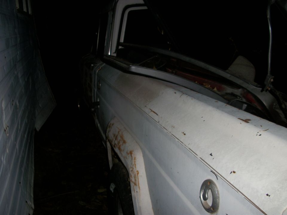old white pickup truck parked in a narrow space, hood is open