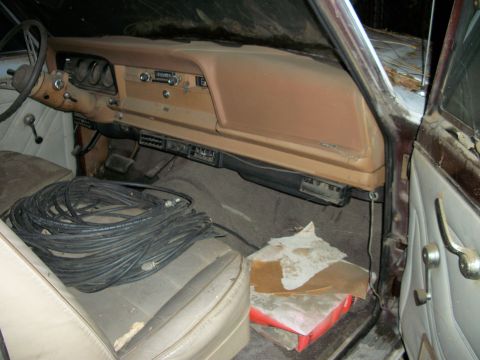 1976 Jeep J-10 - The interior of a 1976 Jeep J-10 shows a tan dashboard with gauges and a radio, and beige seats with a large coil of black cable.