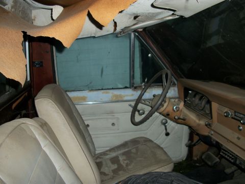 1976 Jeep J-10 - The interior of a 1976 Jeep J-10 shows significant wear, including a damaged headliner and stained upholstery.