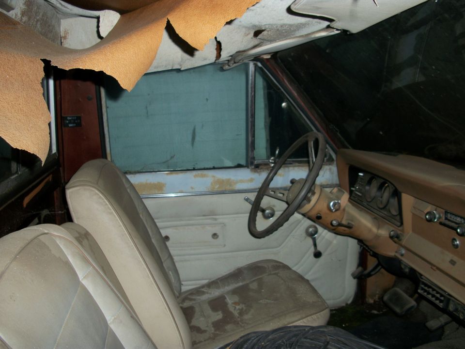 Interior of a 1976 Jeep J-10 with torn headliner and worn seats